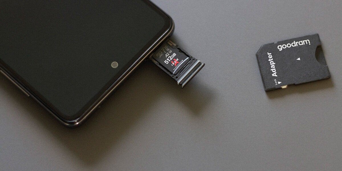 Karta pamięci Goodram M2AA-0640R12 64GB microSDXC UHS-I w slocie na kartę pamięci w telefonie na biurku