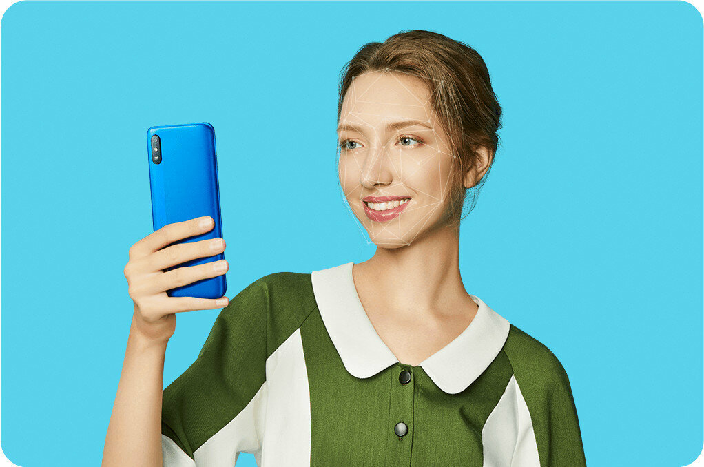 Smartfon Xiaomi Redmi 9A widok na tył telefonu trzymanego w dłoni przez kobietę w trakcie odblokowywania telefonu przy pomocy funkcji AI Face Unlock