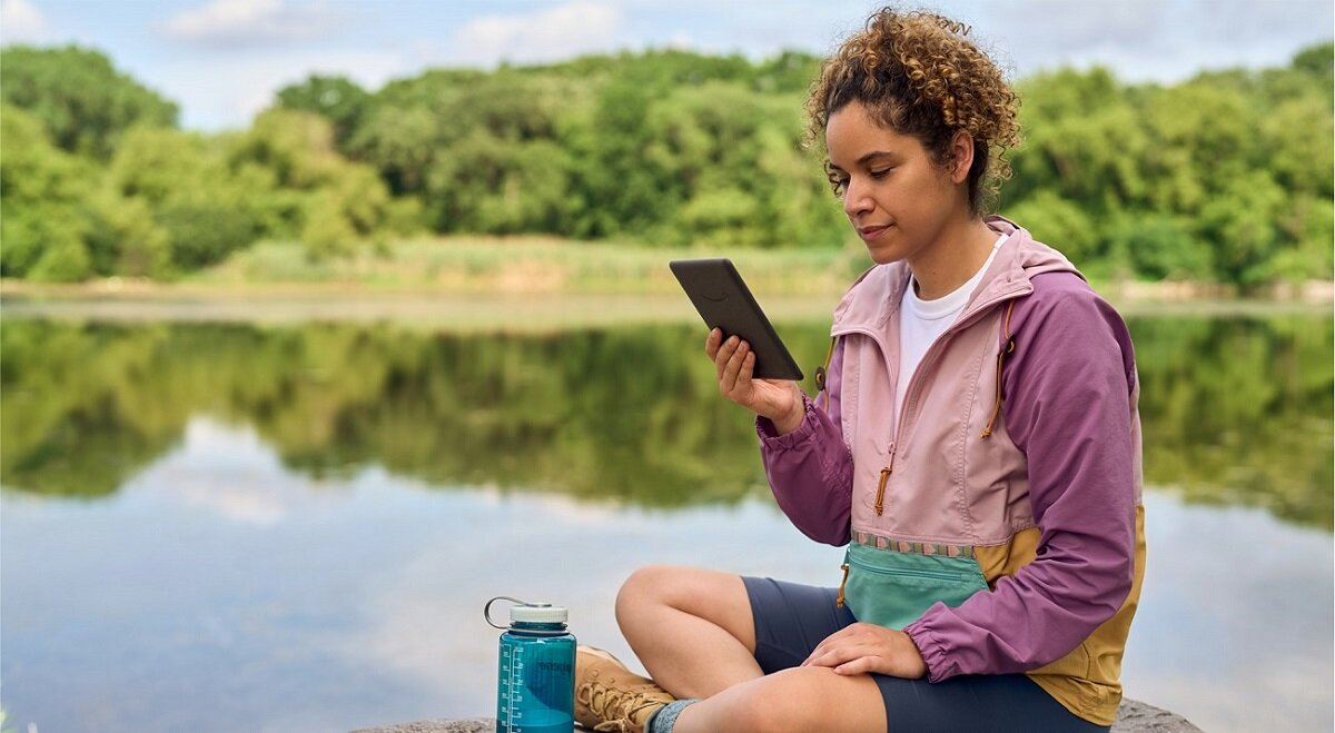 Czytnik ebook Amazon Kindle Paperwhite 5 16 GB czarny widok na kobietę korzystającą z czytnika ebook nad jeziorem