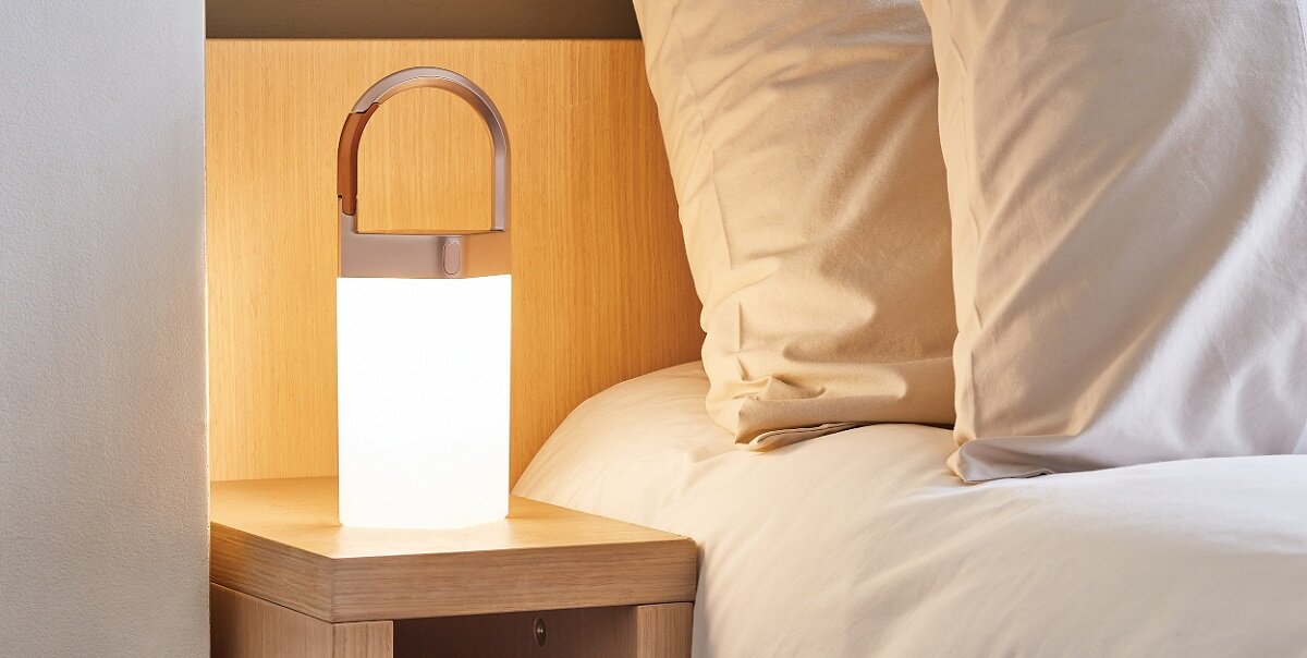 Lampa Lexon Horizon LED szara postawiona na szafce nocnej