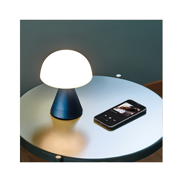 Lampa LED z głośnikiem Lexon Mina LH76MD złota na stoliku obok smartfona widoczna z góry