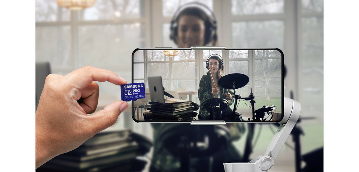Karta pamięci microSD Samsung PRO Plus 2023 + czytnik na tle smartfona w uchwycie podczas nagrywania dziewczyny grającej na perkusji