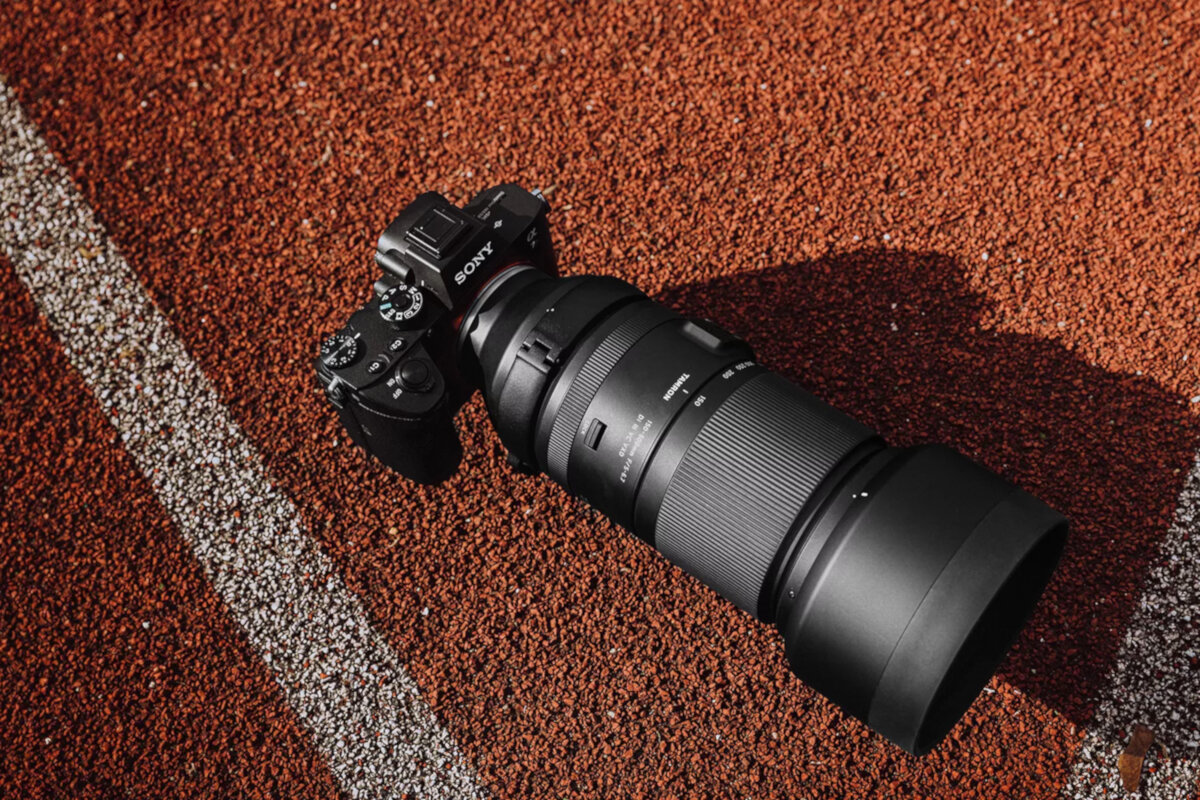 Obiektyw Tamron A057S 150-500 mm F/5-6.7 grafika przedstawia obiektyw z aparatem leżący na boisku