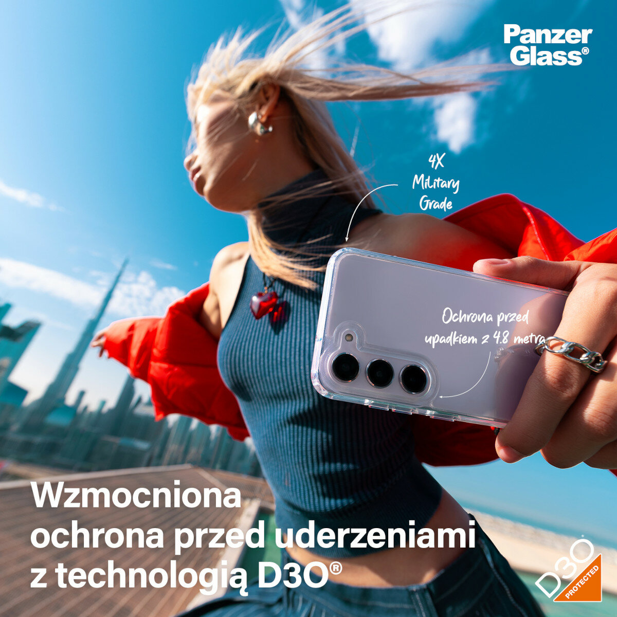 Etui PanzerGlass HardCase D3O Samsung Galaxy S24 przezroczyste widok na kobietę trzymającą telefon z założonym etui na tle wieżowców 