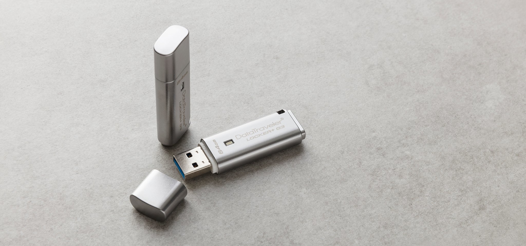 Pamięć Kingston 32GB DataTraveler Locker+ G3 USB 3.0 135MB/s DTLPG3/32GB szary widok od przodu na dwa produkty, jeden pendrive ze zdjętą osłoną portu